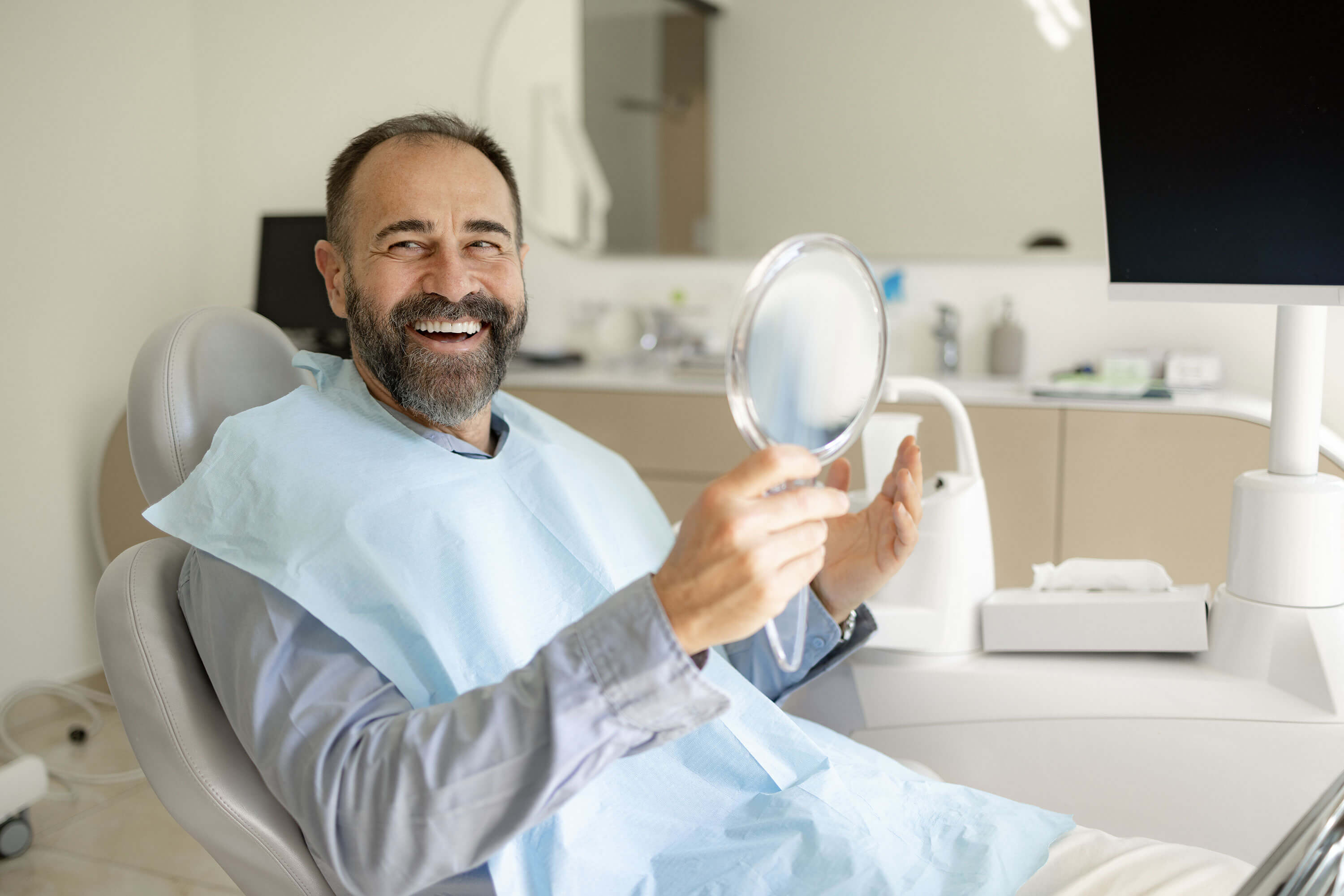 Male in dental chair smiling while looking in the mirror